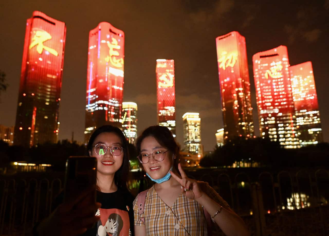 People take pictures on the eve of the 100th anniversary in Beijing. 