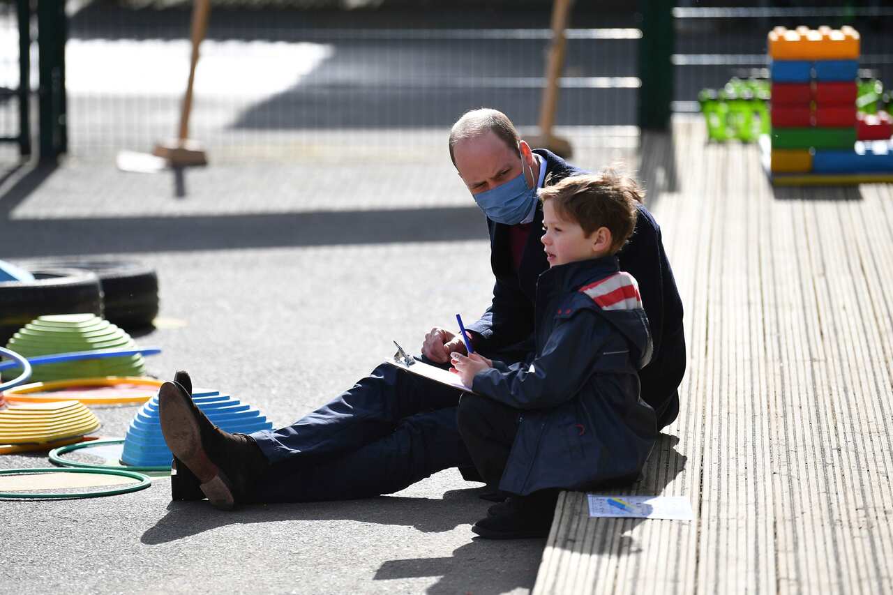 Britain's Prince William talks with a child in the playground during a visit with Kate, Duchess of Cambridge to School21.