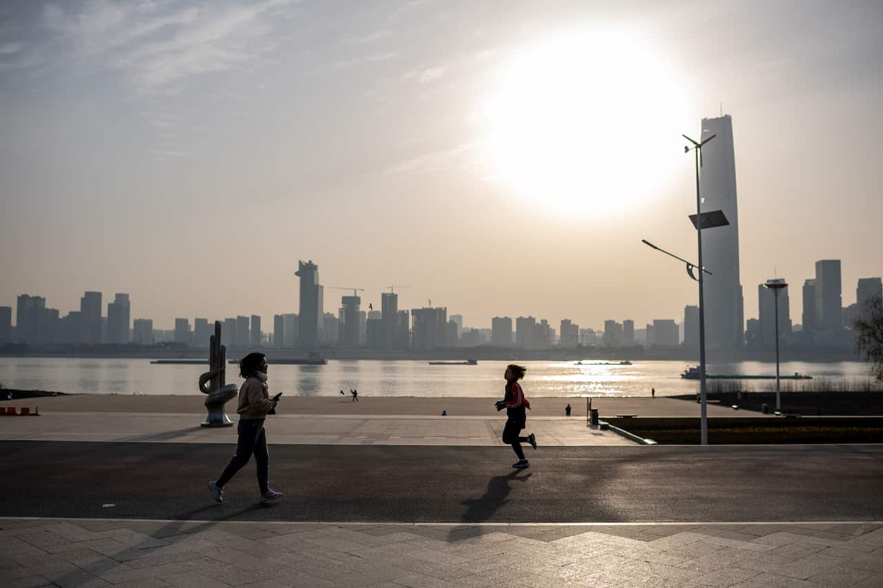 People run along the banks of the Yangtze River in Wuhan on 11 January, as the city marks the first anniversary of China confirming its first COVID-19 death.