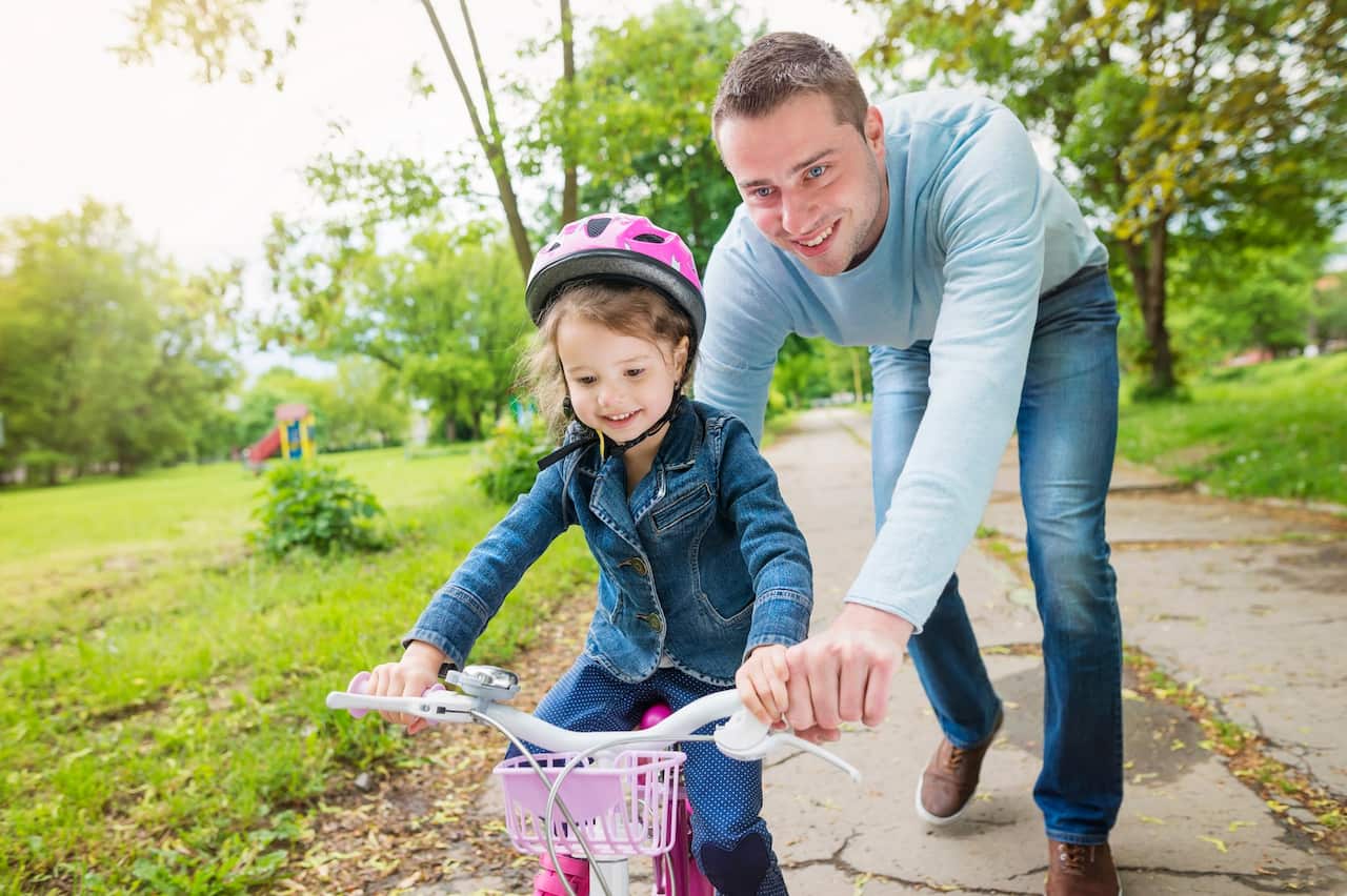 Father accompanying daughter on bike