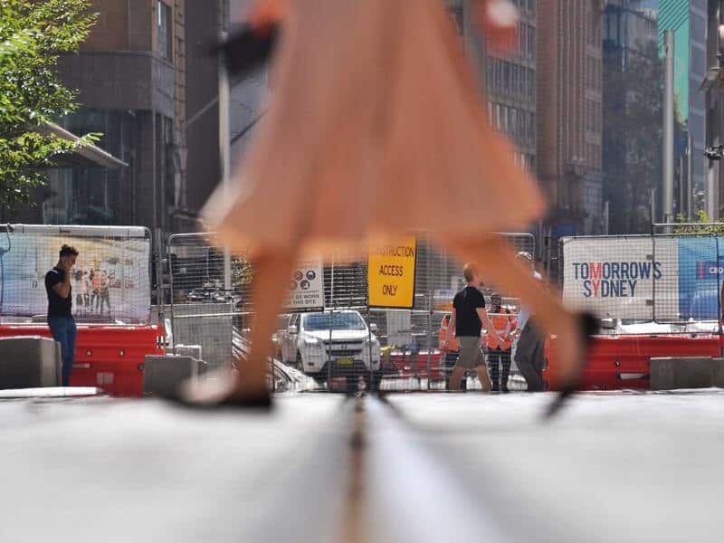Pedestrians walk past the Sydney CBD Light Rail Project construction.