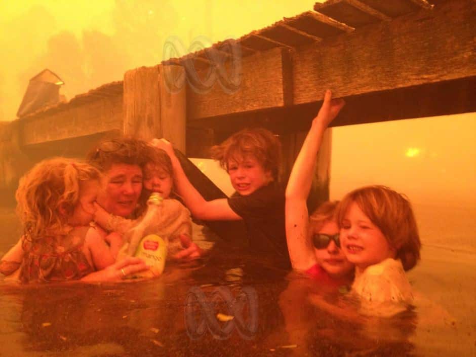 Tammy Holmes is seen taking refuge with her grandchildren under a jetty as a bushfire engulfed the Tasmanian town of Dunalley in January, 2013.