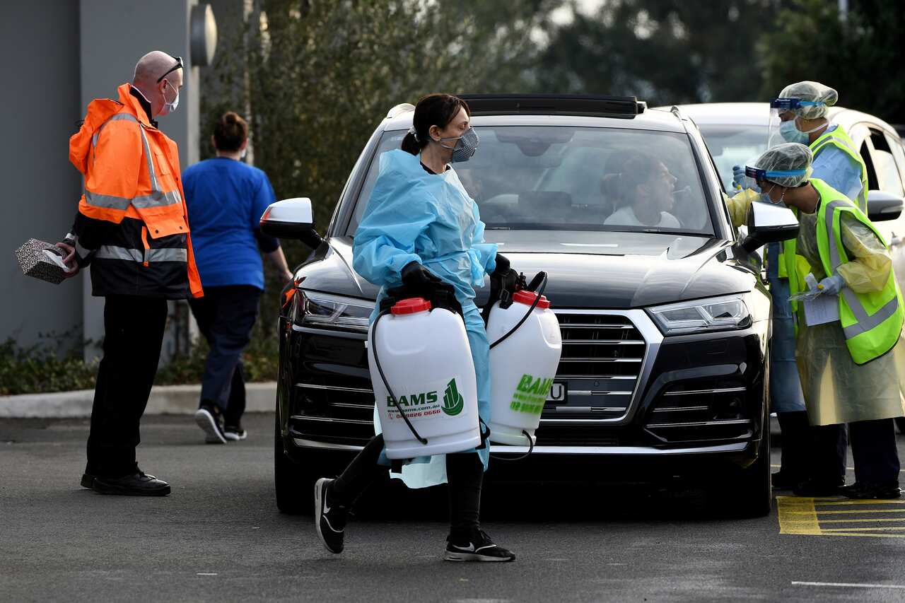 A cleaner dressed in Personal Protective Equipment leaves the Crossroads Hotel.