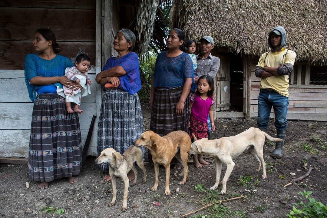 Members of the Caal Maquin family and neighbours stand in front of Claudia Maquin's house in Raxruha, Guatemala.