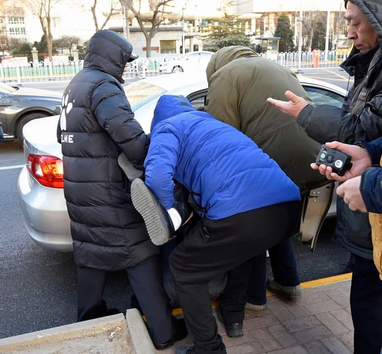 A supporter of Chinese civil rights lawyer Wang Quanzhang is pushed into a car by Chinese officials near the Tianjin Second Intermediate People's Court.