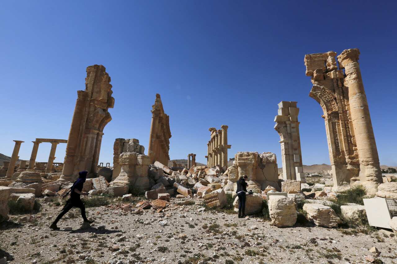 Jounalists walk near the remains of the Monumental Arch in the historic Syrian city of Palmyra in April last year.