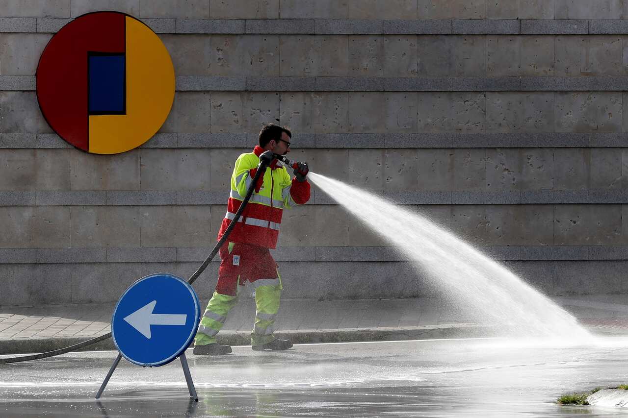  worker cleans the street at the entrance to the Ifema Fair ground where a provisional hospital for coronavirus patients is set up in Madrid, Spain.