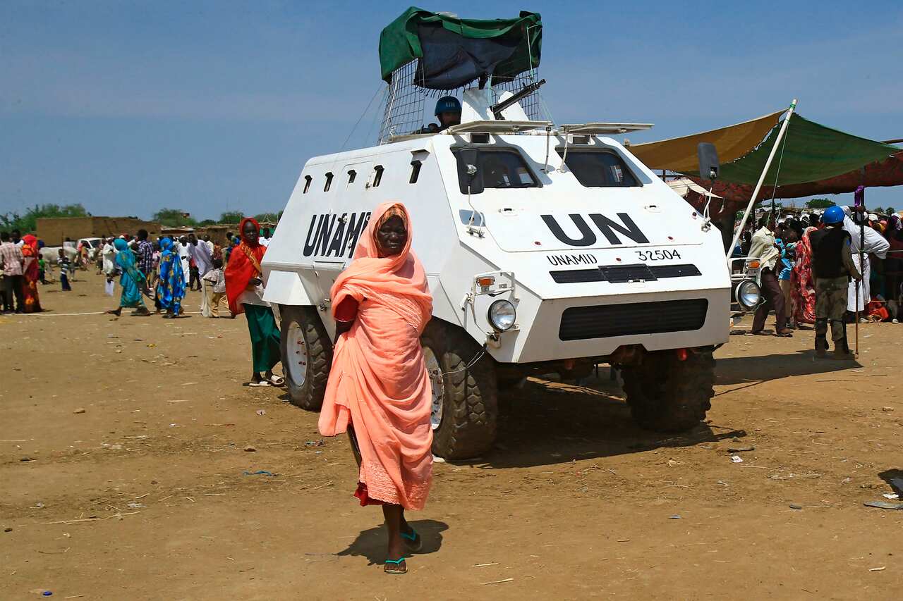 A displaced Sudanese woman walks past a UNAMID vehicle at the Kalma camp for internally displaced people in Darfur's state capital Niyala on 9 October, 2019.