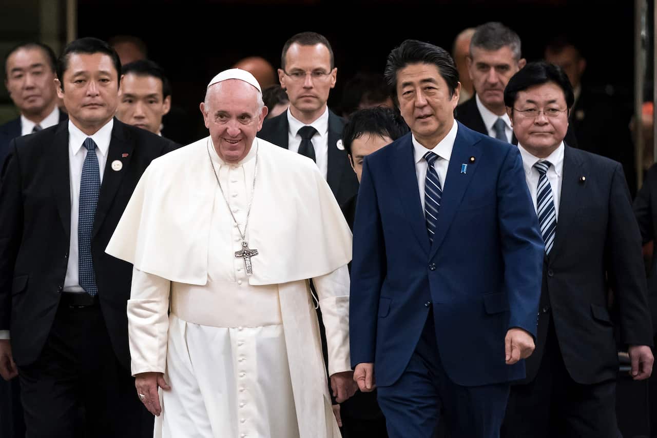 Pope Francis walks with Japan's Prime Minister Shinzo Abe as he arrives in Tokyo.