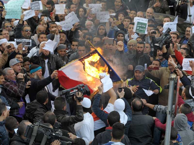 Demonstrators burn a representation of a French flag during a protest