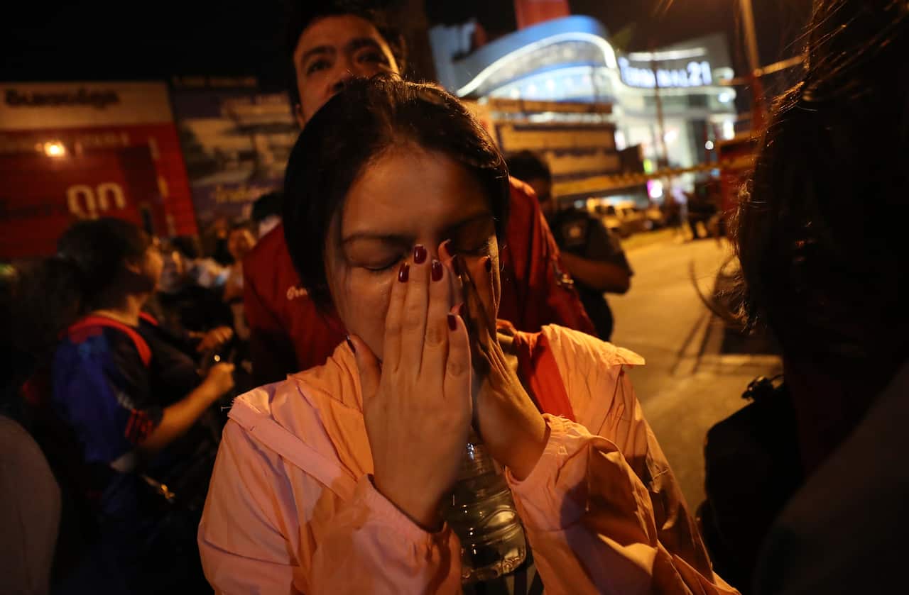 A woman who was able to get out of Terminal 21 Korat mall gestures with her hands on her face in Nakhon Ratchasima.