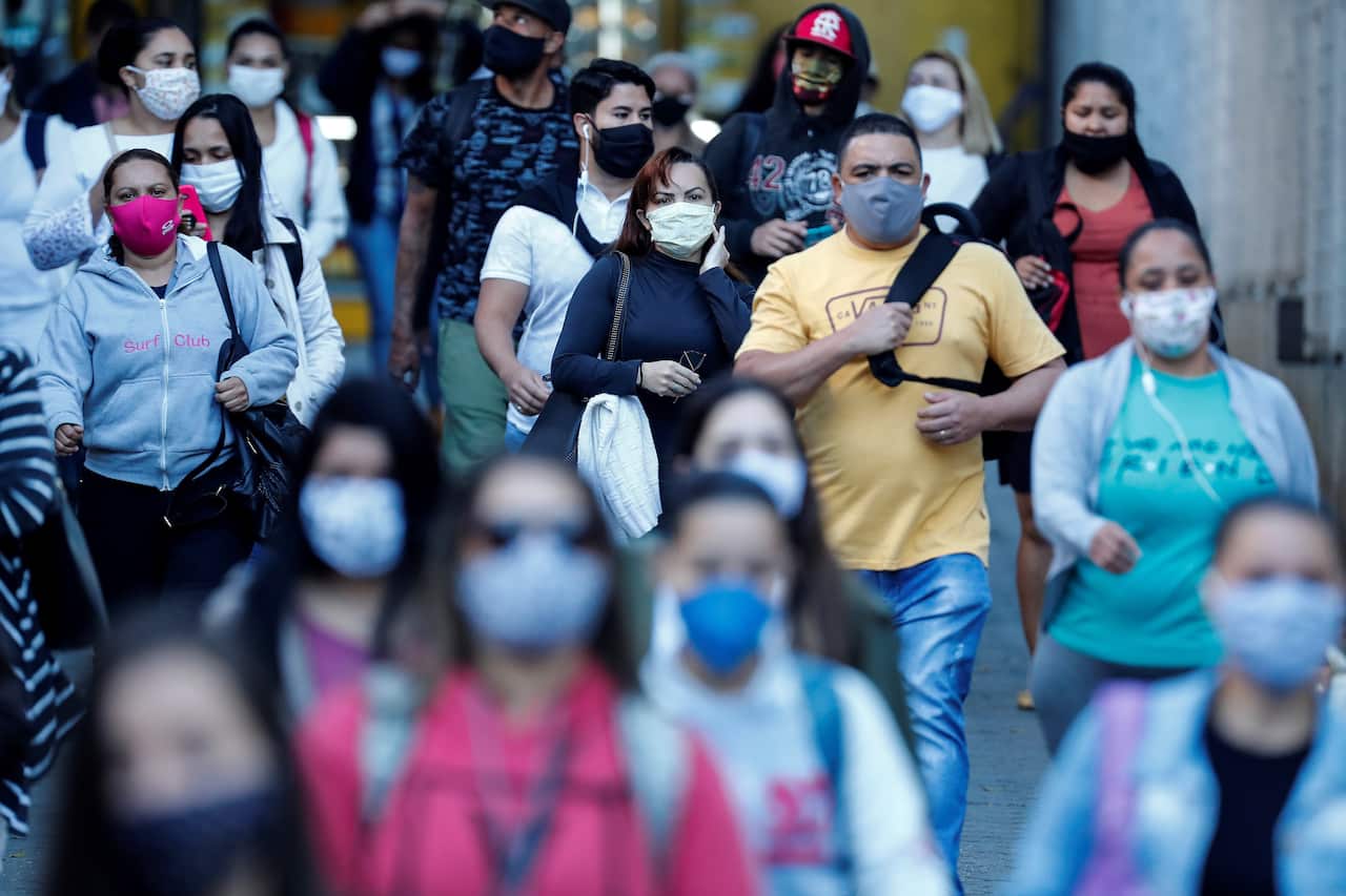 People with face masks walk in a street amid coronavirus pandemic in Sao Paulo, Brazil.