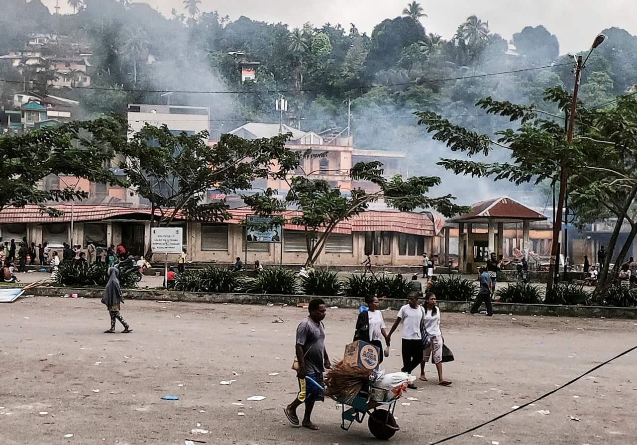 Papuans carry their belongings as they flee after a violent protest.
