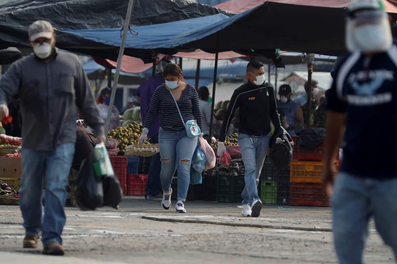 People with facial masks walk through a street market authorised by the government, in Tegucigalpa, Honduras.