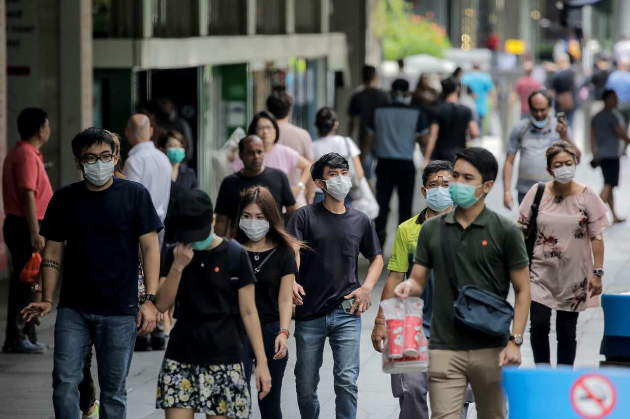 People, wearing face masks, walk past a shopping mall  in Singapore, 7 April 2020.