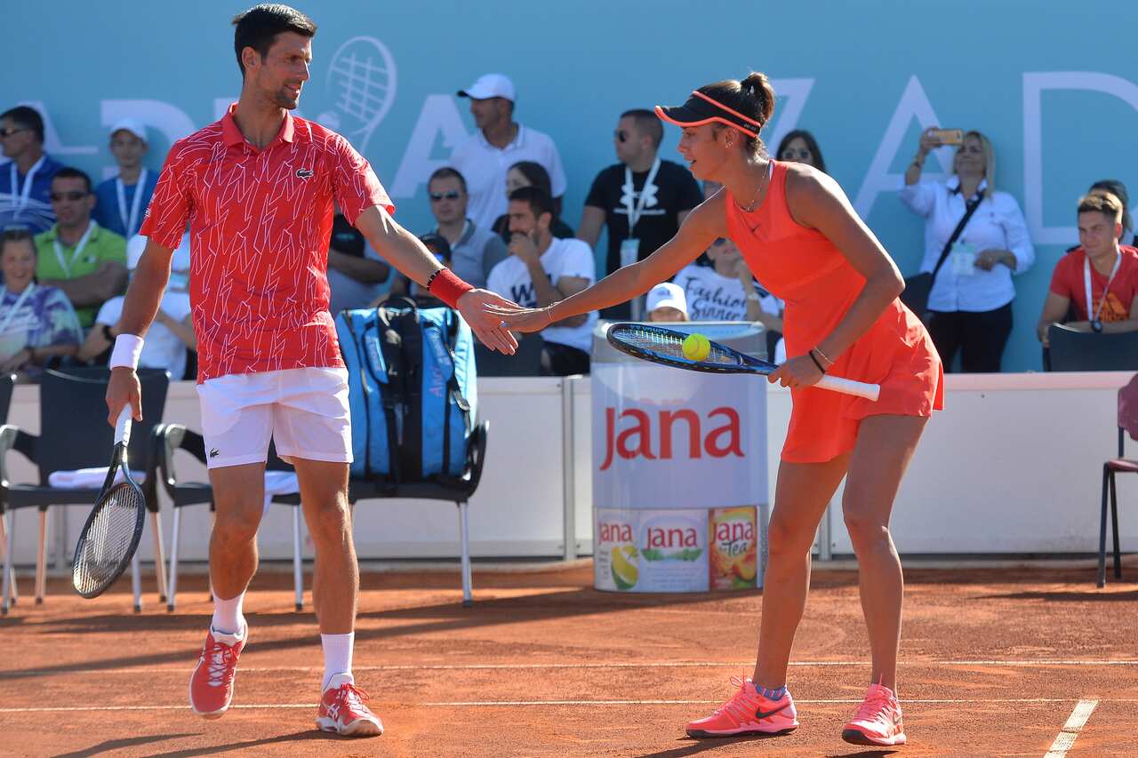 Serbian tennis player Novak Djokovic touches hands with Olga Danilovic during their mixed doubles match.