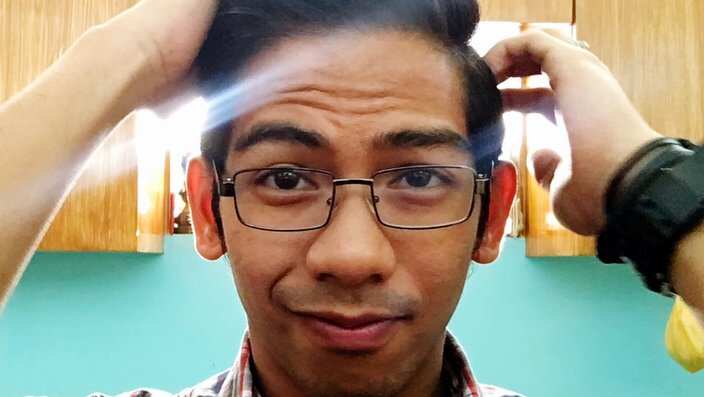 Portrait Of Confused Young Man With Hand In Hair At Home