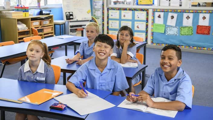Portrait of five multi racial school children sitting at desks in clasroom