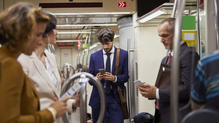 Businessman using cell phone on subway train