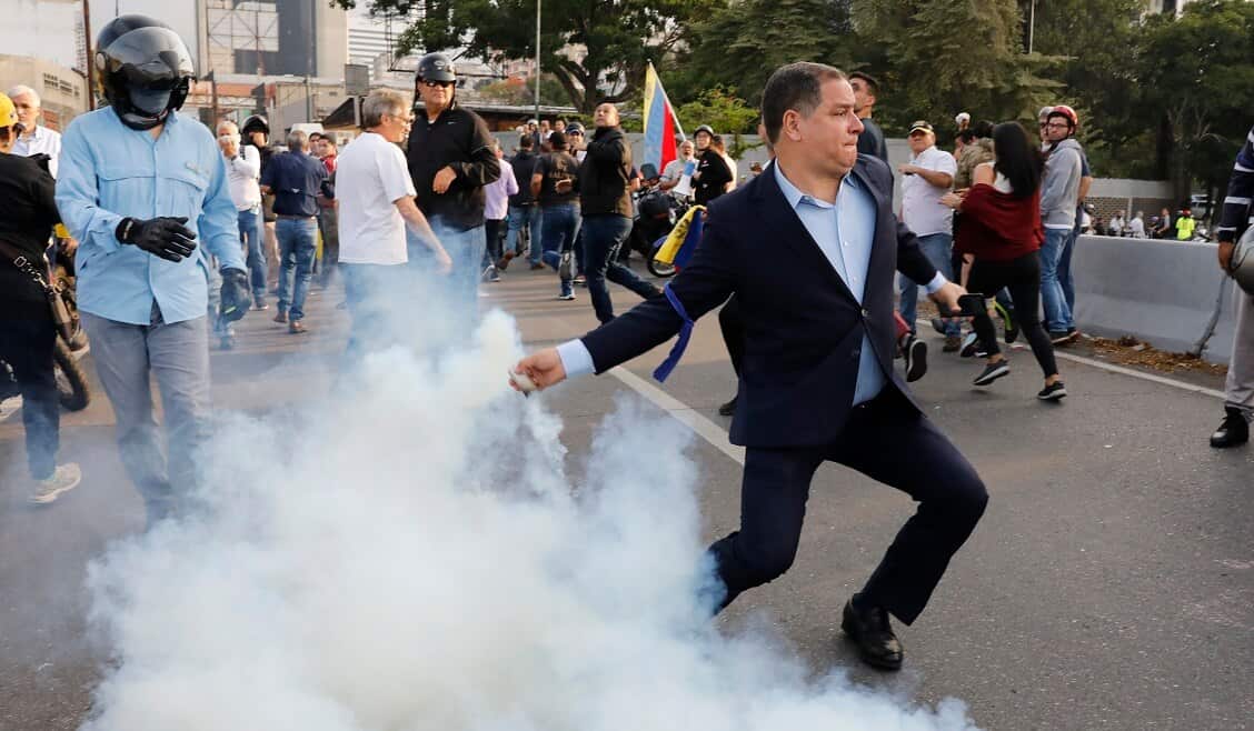 An opponent to Venezuela's President Nicolas Maduro returns a tear gas canister in Caracas.