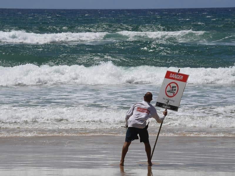 A lifeguard places a danger sign on the Gold Coast.