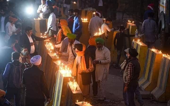 A group of farmers putting candles on the barricades used to stop them to march ahead at Delhi border.