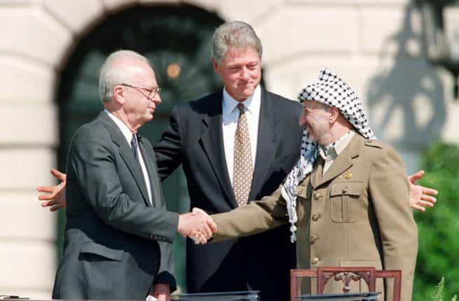 US President Bill Clinton stands between PLO leader Yasser Arafat and Israeli Prime Minister Yitzhak Rabin as they shake hands for the first time, on Sept. 13, 1993