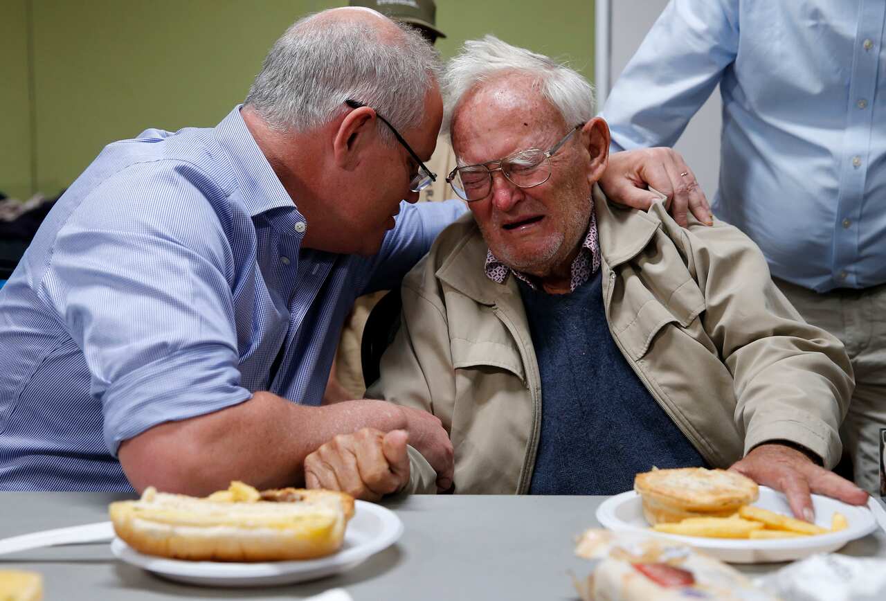 Prime Minister Scott Morrison comforts a man who escaped bushfires during a visit to an evacuation centre on Sunday. 