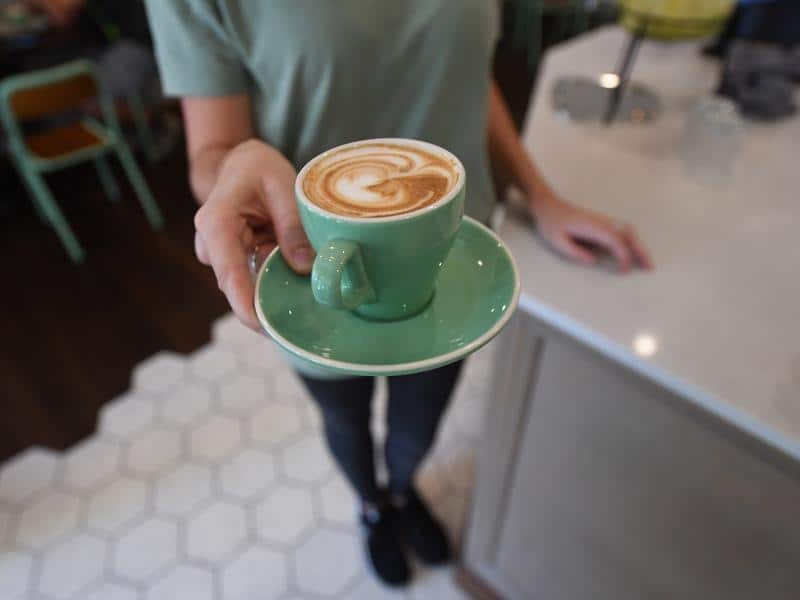 A waitress is seen holding a coffee at a cafe