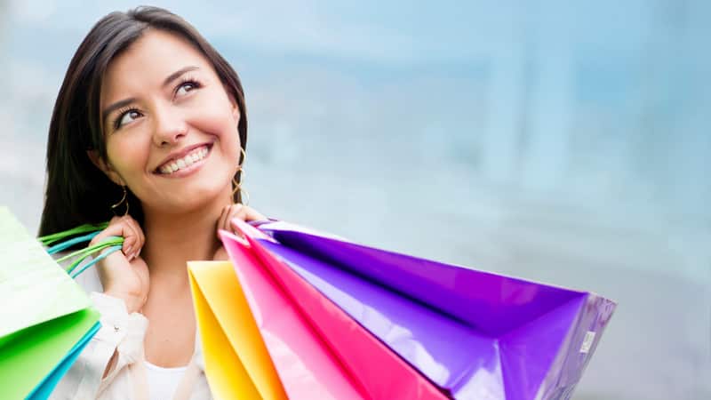 Thoughtful woman holding shopping bags and looking up
