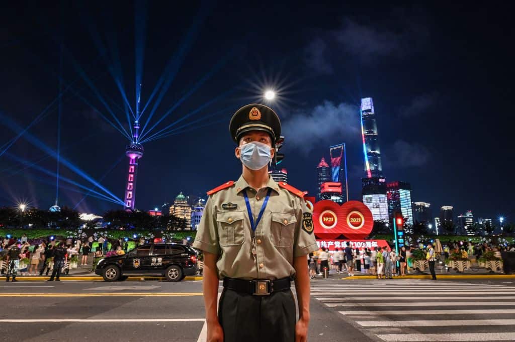 A Chinese paramilitary police stands guard amid a light show for the anniversary in Shanghai. 