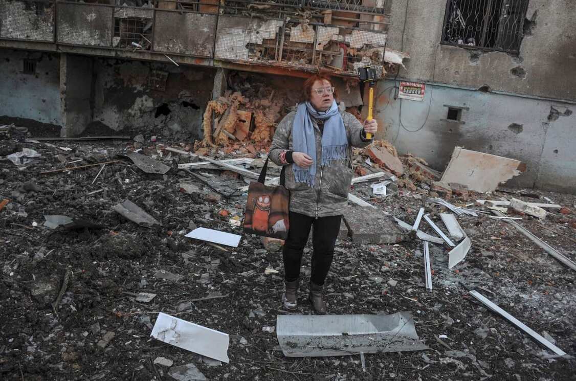 A woman stands next to a damaged building in the aftermath of shelling in Kharkiv, Ukraine, on 17 March 2022.