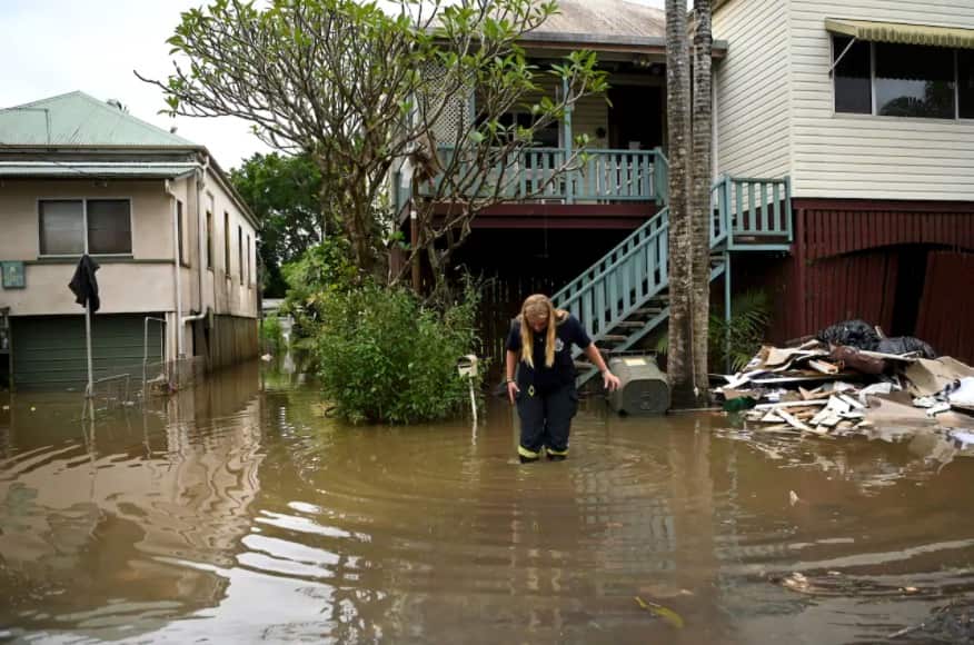 A rural fire service volunteer inspects a house surrounded by floodwater on 31 March, 2022 in Lismore, NSW.