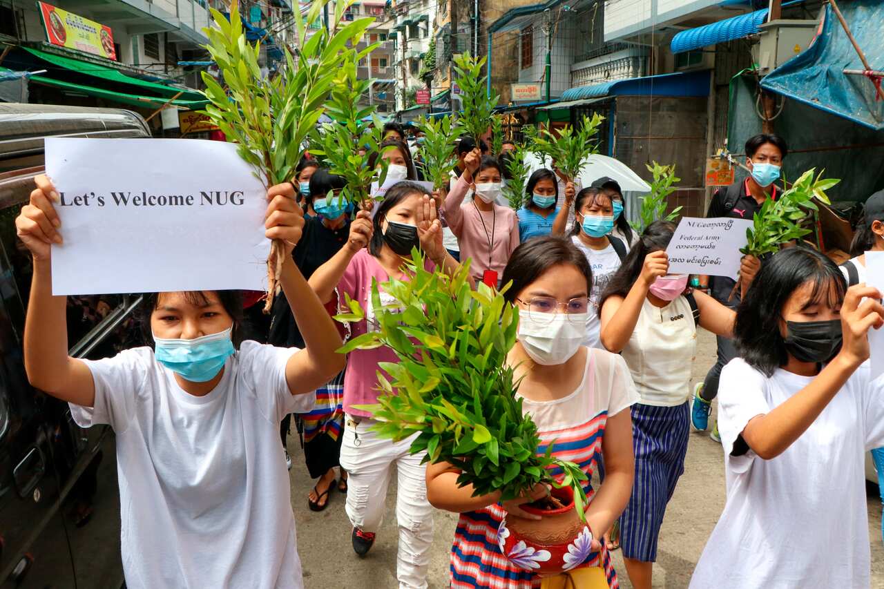 Anti-coup protesters hold leaf branches and signs to welcome the NUG, or national unity government as they march in Yangon, Myanmar