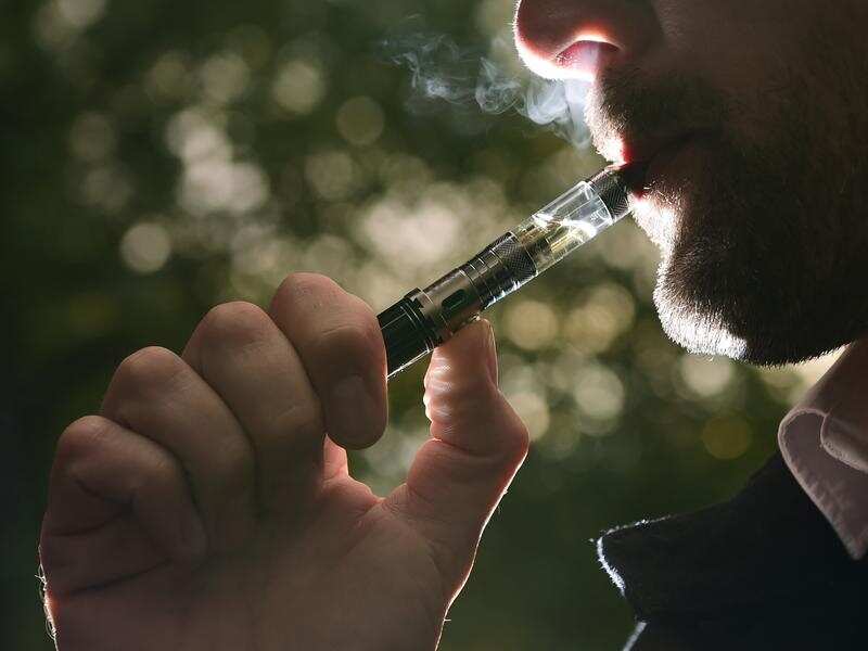 Close up photograph of man smoking an electronic cigarette.