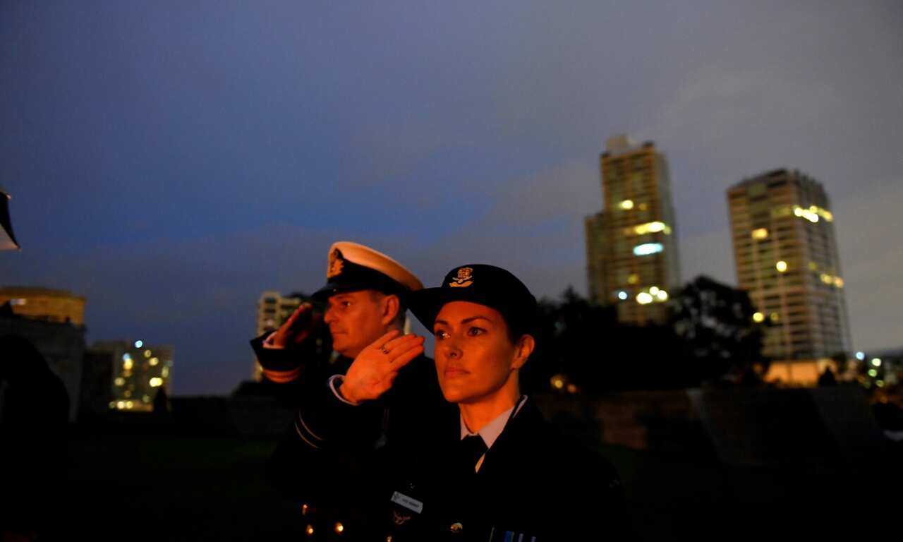 Flight Lieutenant Kate Kennedy and Lieutenant Ben Willee salute durung the Anzac Day Dawn Service during Anzac Day commemorations in Melbourne (AAP)