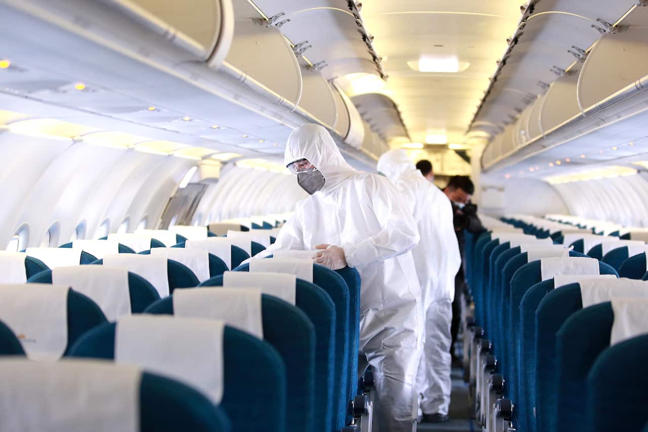 Workers prepare to spray disinfectant as a precaution against the coronavirus, inside a Vietnam Airlines airplane in Hanoi, Vietnam 3 March 2020. 