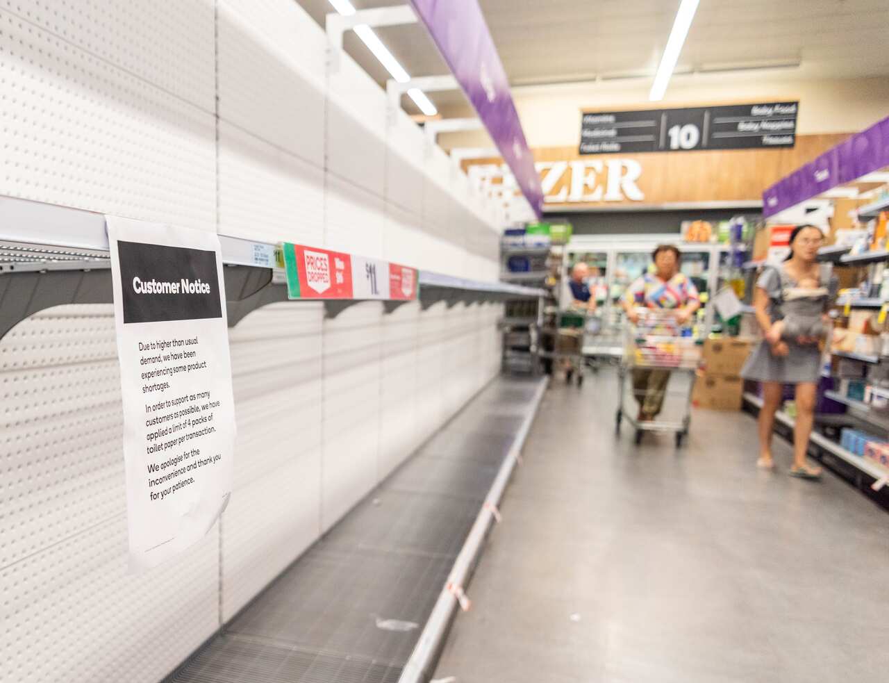 Customers looks at empty shelves at a supermarket.