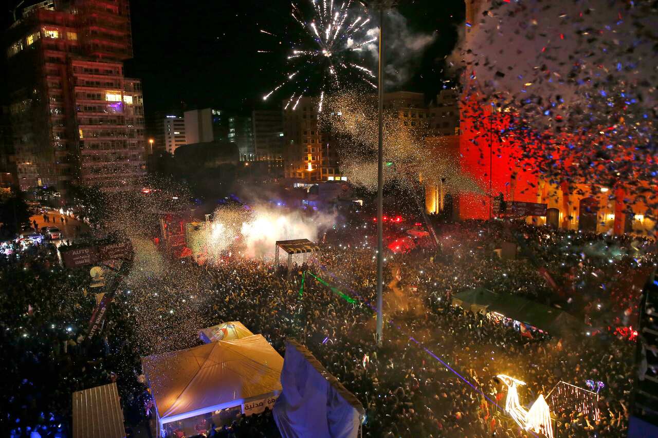 Thousands of anti-government protesters and citizens watch a firework display during the New Year's celebrations in Martyrs' Square in downtown Beirut, Lebanon.
