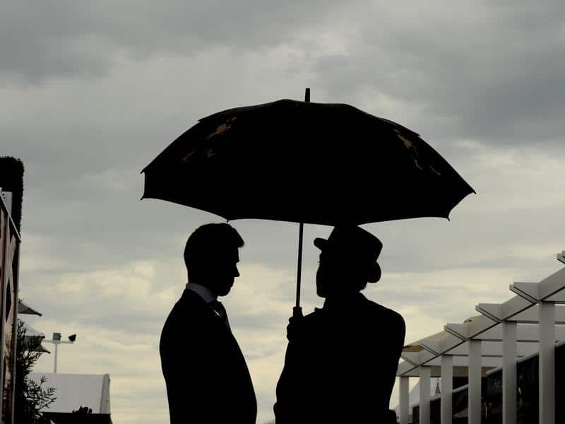 A file image of racegoers sheltering under an umbrella at Flemington
