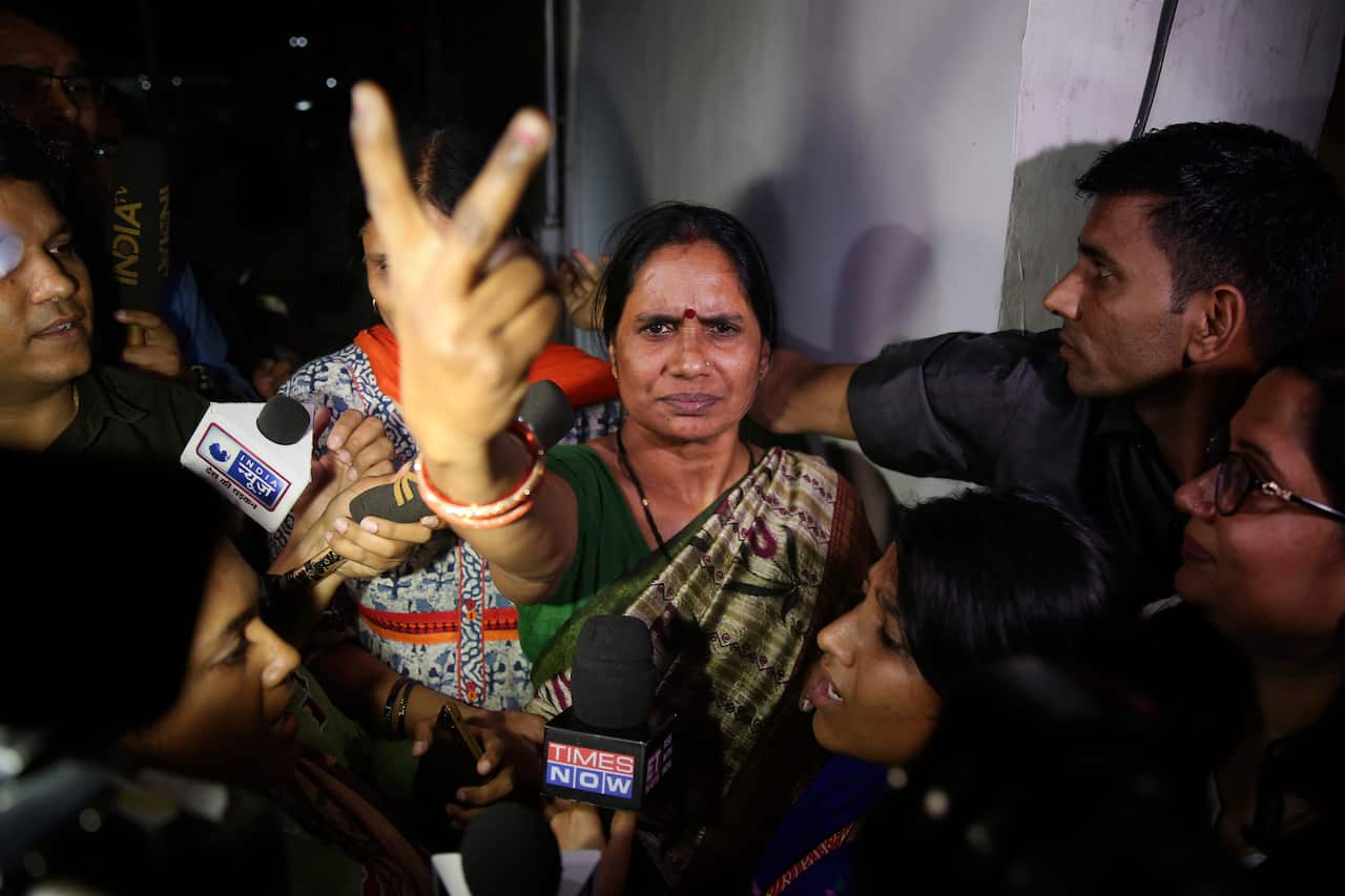 Asha Devi, mother of the victim of the fatal 2012 gang rape on a moving bus, displays a victory sign after the rapists of her daughter were hanged in New Delhi.
