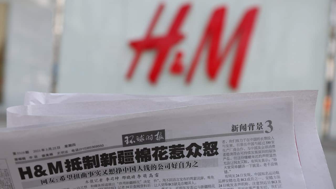 A newspaper with a report about H&M is seen in front of a H&M logo