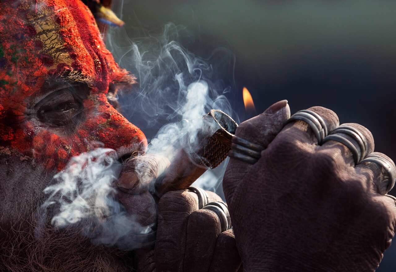 A sadhu, or holy man, smokes marijuana from a clay pipe at the Pashupati Temple in Kathmandu
