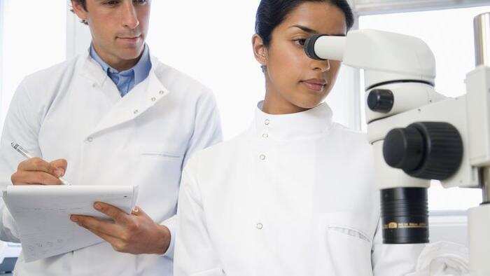 Scientists using microscope in laboratory