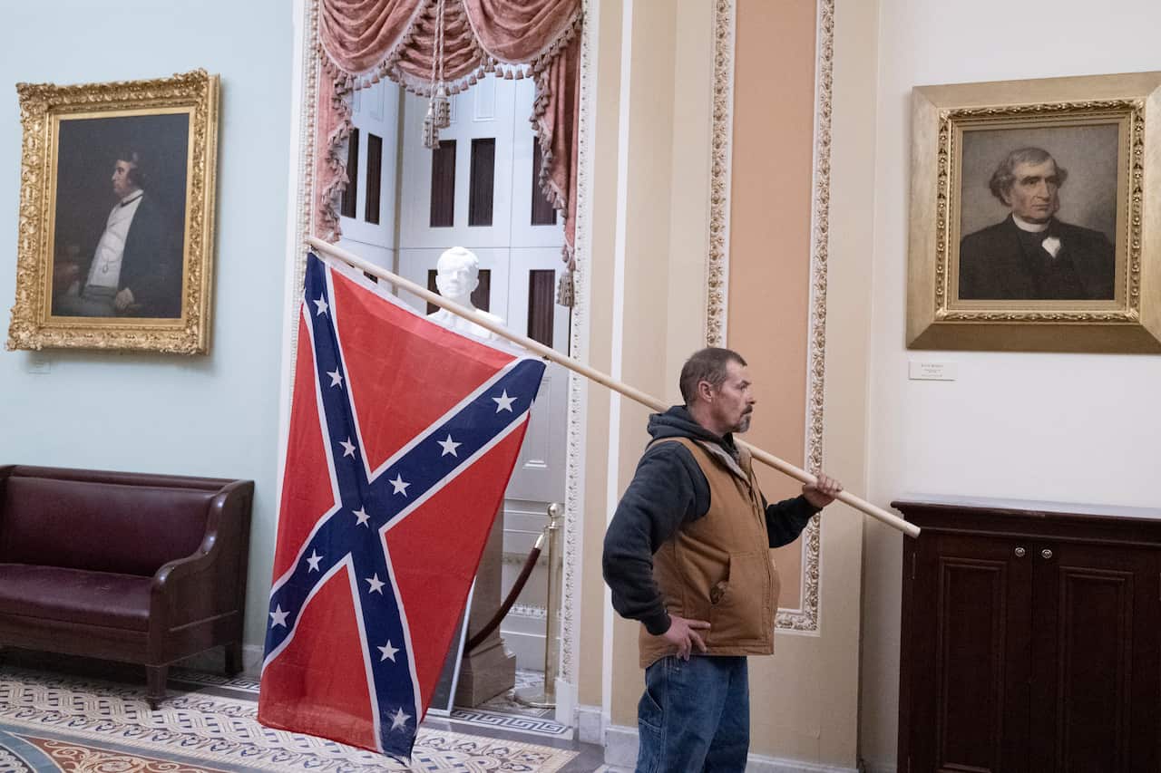 6 January 2021- Washington DC- A protester stands with a Confederate flag after storming the Capitol during a Joint Session of Congress in which members were to certify the 2020 Presidential election. Photo Credit: Chris Kleponis/Sipa USA