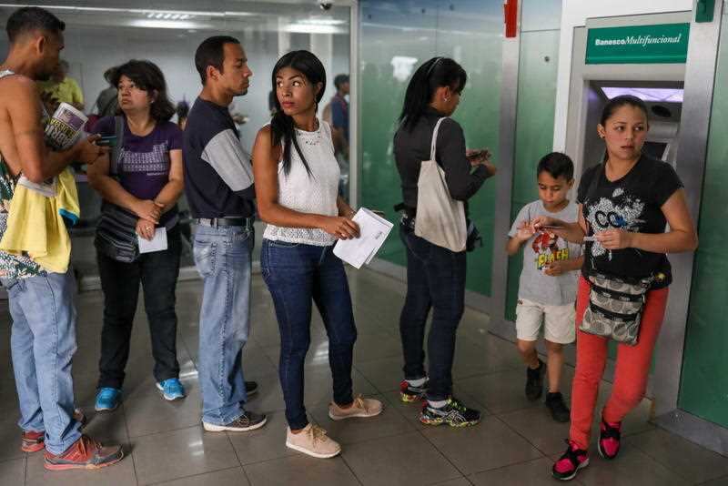 Clients queue at a banking institution to withdraw money from the entity, in Caracas, Venezuela, 21 August 2018.