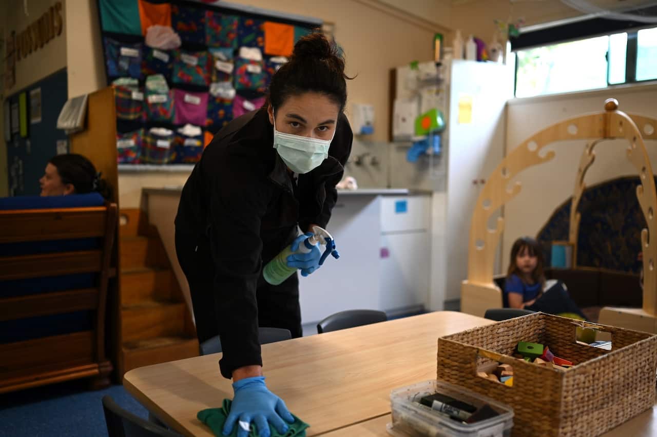 Early childhood educator Josephine wipes down tables and bench tops with disinfectant at the Robertson Street Kindy Childcare Centre in Helensburgh, NSW