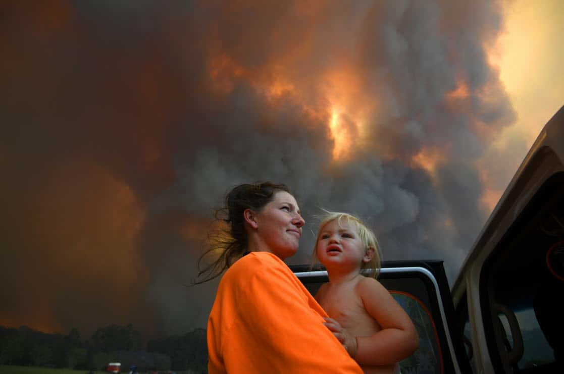 Sharnie Moren and her 18 months old daughter Charlotte look on as thick smoke rises from bushfires near Nana Glen, near Coffs Harbour, Tuesday, 12 November