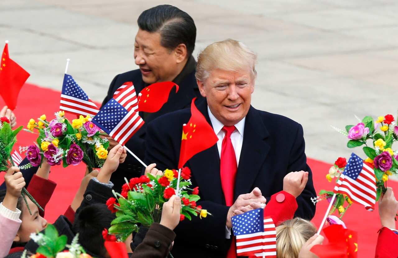 US President Donald Trump, right, and Chinese President Xi Jinping are greeted by children waving flowers and flags during a welcome ceremony 