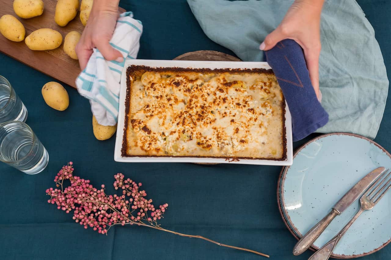 Woman serving potato mincemeat gratin, partial view